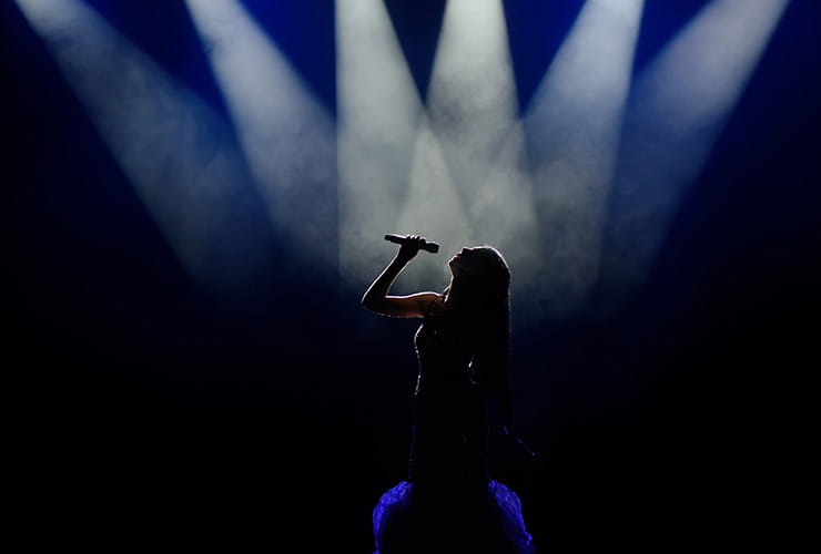 A female singer performing while in the spotlights