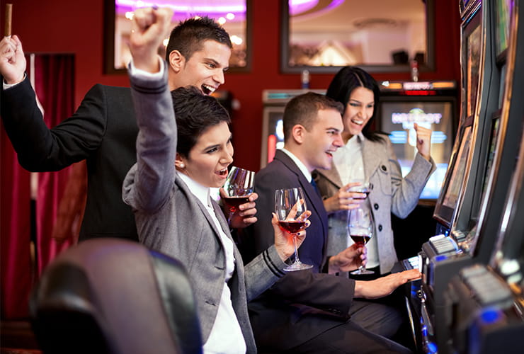 A group of people having a drink and enjoying the wins while playing at the slot machines