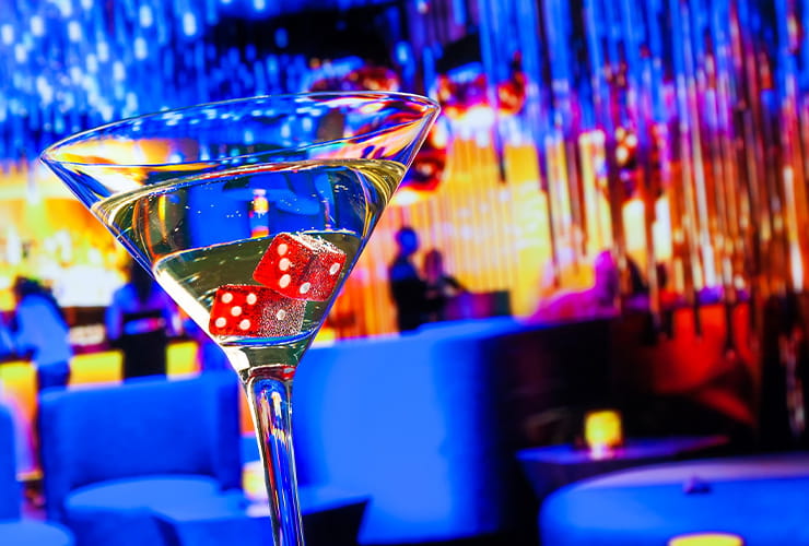 A glass filled with martini and two red dices laying at the bottom of it