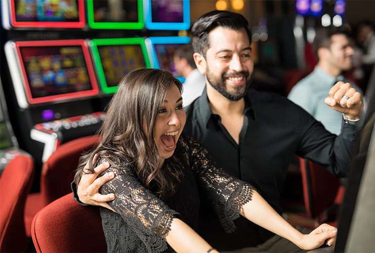 A young couple enjoying a win while playing at the slot machines